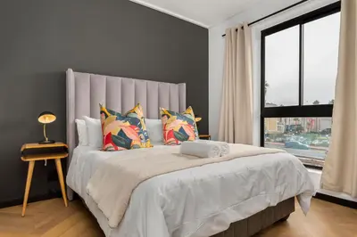 a bedroom with a large bed with pillows and a window at Nine Palms Stunning 1-Bedroom Apartment in Century City
