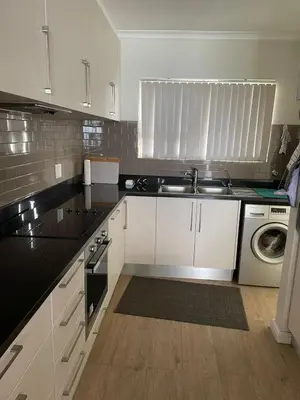 a kitchen with white cabinets and black counter tops at 510 Odeon Towers - SeaView in Strand