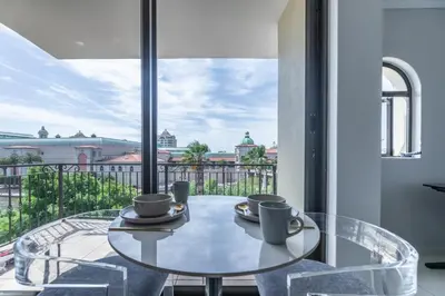 a glass table with two coffee cups on a balcony at St Tropez On Lake 302 The Island Club in Cape Town