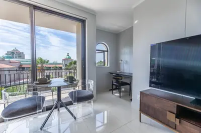 a living room with a large television and a table and chairs at St Tropez On Lake 302 The Island Club in Cape Town