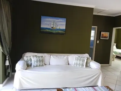 a white couch in a living room with a painting of a ship at Carmel Huys in Cape Town