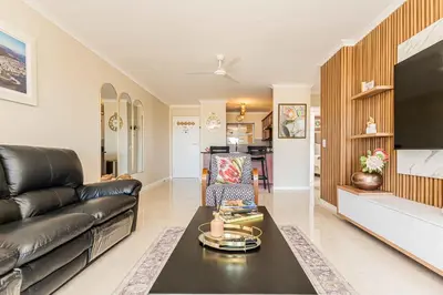 a living room with a black leather couch and a tv at Bella View in Cape Town