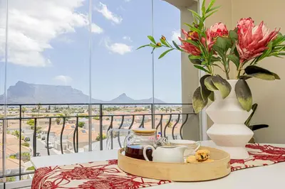 a table with a vase of flowers and a tray of tea cups at Bella View in Cape Town