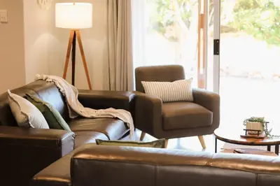a living room with a leather couch and a chair at Rissie's Villa in Gordonʼs Bay