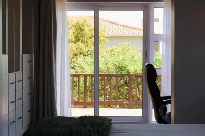 a bedroom with a sliding glass door to a balcony at Rissie's Villa in Gordonʼs Bay