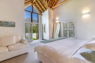 a white bedroom with a large bed and a couch at Farm House with Pool & Never Ending Mountain Views in Stellenbosch