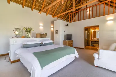a bedroom with a large white bed and a couch at Farm House with Pool & Never Ending Mountain Views in Stellenbosch