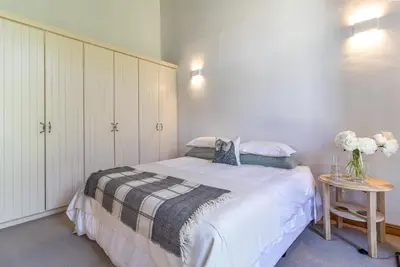 a bedroom with a bed and a table with flowers at Farm House with Pool & Never Ending Mountain Views in Stellenbosch