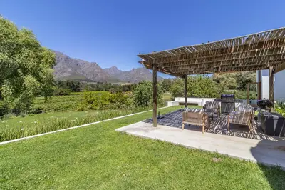 a patio with a table and chairs under a pergola at Farm House with Pool & Never Ending Mountain Views in Stellenbosch