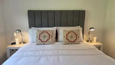 a white bed with two pillows and two lamps at Swallows Nest Garden Cottage in Helderberg