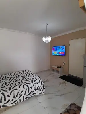 a bedroom with a black and white bed and a tv at Livingsound 1bed self cat apartment in Cape Town