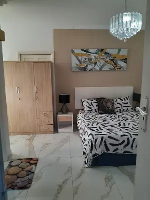 a bedroom with a zebra print bed and a chandelier at Livingsound 1bed self cat apartment in Cape Town