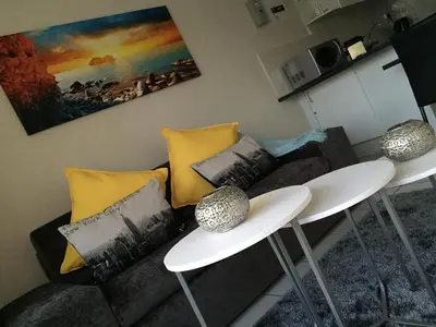 a living room with two white tables and a couch at 10 South Views in Bloubergstrand