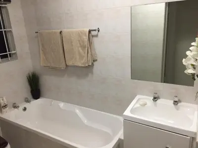 a bathroom with a white tub and a sink at 10 South Views in Bloubergstrand