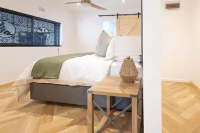 a bedroom with a bed and a table with a lamp at Villa Noor Modern 2 Bed Luxury Retreat in Hanover Park