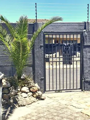 a gate with a palm tree in front of a building at Central, Spacious GF Apartment, access to N1,N2,M5