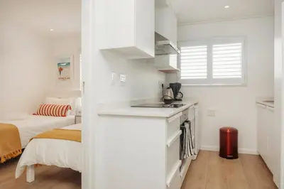 a small white kitchen with a sink and a bed at Hermanus Beach Club 218 in Hermanus