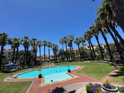 a swimming pool with palm trees in a park at Family Oasis with Pool close to Shopping Center in Cape Town