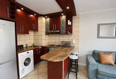 a small kitchen with a counter and a washer and dryer at 3B Sandy Bay in Cape Town