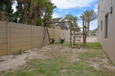 a wooden fence with a swing on the side of a house at 3B Sandy Bay in Cape Town