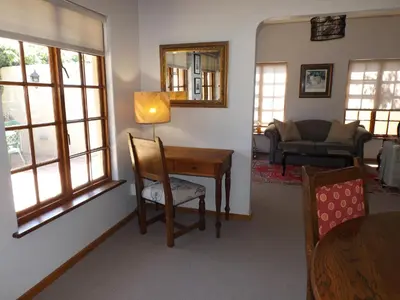 a living room with a table and a chair at Ambleside House Pinelands, Cape Town in Cape Town
