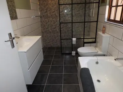 a bathroom with a tub and a toilet and a sink at Ambleside House Pinelands, Cape Town in Cape Town