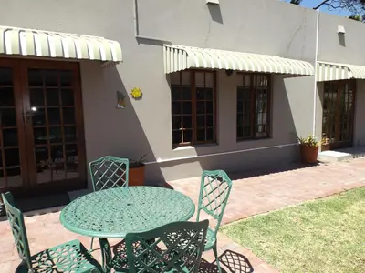 a table and chairs in front of a house at Ambleside House Pinelands, Cape Town in Cape Town