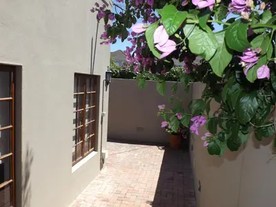 an alley with flowers hanging from a building at Ambleside House Pinelands, Cape Town in Cape Town