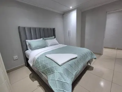 a bedroom with a large bed with a gray headboard at Maglovir economy 3 BEDROOMS BULK in Tiervlei