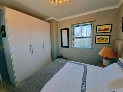 a bedroom with a large bed and a chandelier at Beach Walk Guest House & Apartments in Cape Town
