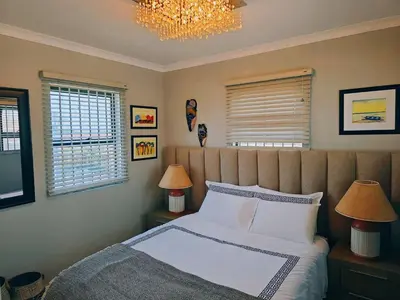 a bedroom with a bed and two lamps and a chandelier at Beach Walk Guest House & Apartments in Cape Town