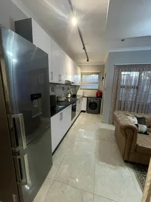 a kitchen with a refrigerator and a couch in a room at Beach Walk Guest House & Apartments in Cape Town