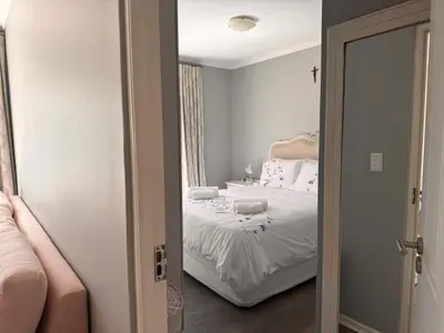 a bedroom with a bed with white sheets at Divine Favor House on 44 Torrington in Cape Town