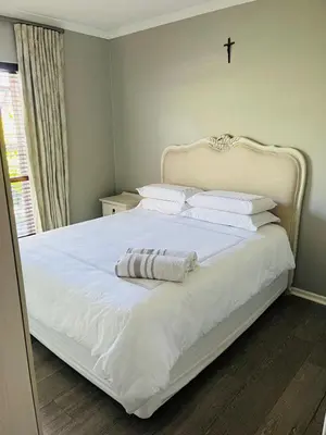 a white bed with two towels on top of it at Divine Favor House on 44 Torrington in Cape Town