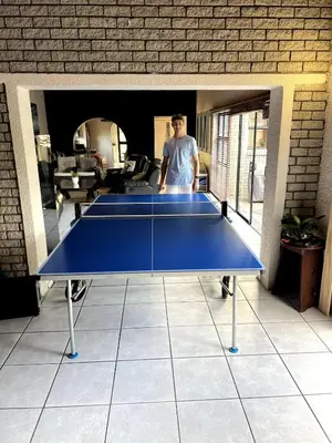 a man standing next to a blue ping pong table at Family Home with Big Garden & Jacuzzi in Welgelegen