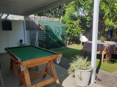 a pool table on a screened in porch with a table at Cozy family home in Cape Town