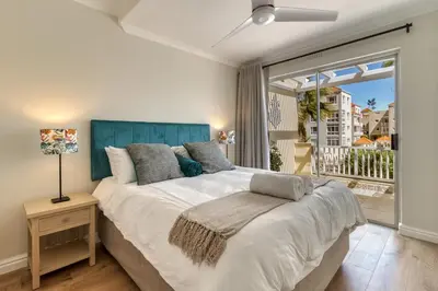 a bedroom with a large bed and a large window at Sunny Apartment Harbour Island in Gordonʼs Bay