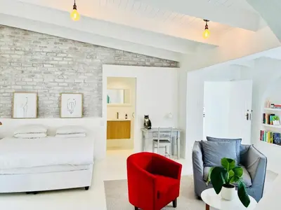 a bedroom with a white bed and a red chair at Northcliff House in Hermanus