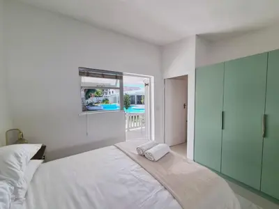a white bedroom with a bed and a window at Northcliff House in Hermanus