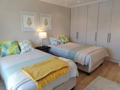 two beds in a small room with white cabinets at Paradise Piet Haven in Hermanus