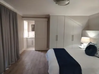 a bedroom with a bed with white cabinets and a window at Paradise Piet Haven in Hermanus