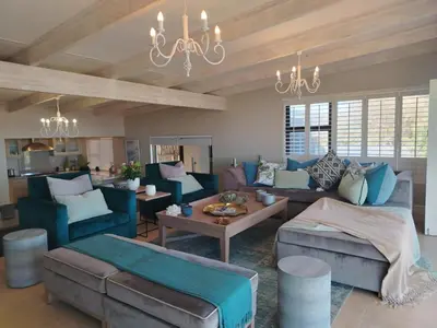 a living room with blue furniture and a chandelier at Paradise Piet Haven in Hermanus