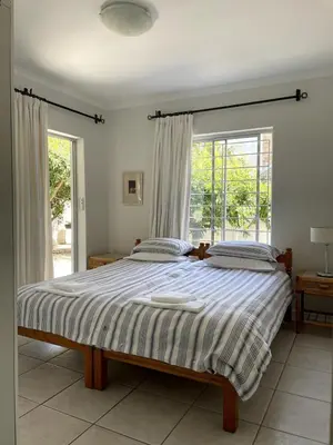 a bedroom with a bed and a large window at Secret Coastal Garden in Hermanus