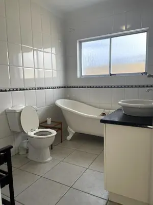 a bathroom with a tub and a toilet and a sink at Secret Coastal Garden in Hermanus