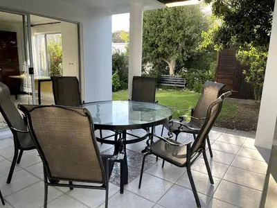 a glass table and chairs on a patio at Secret Coastal Garden in Hermanus