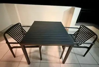 a wooden table and two chairs sitting on a balcony at Luxury Coastal Escape in Strand in Somerset West