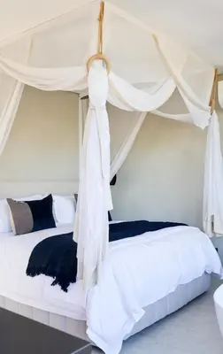 a bedroom with two beds with white curtains at Olijvenkraal Winelands Lodge in Paarl