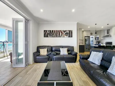 a living room with a couch and a table at Neptune Isle Oceanfront 3-Bed with Pool in Cape Town