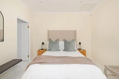 a white bedroom with a large bed with pillows at The Farm Cottage in Franschhoek