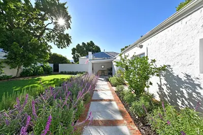 a garden with purple flowers next to a building at The Farm Cottage in Franschhoek